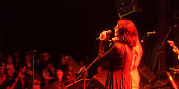 Performer sings to audience with view from stage looking out. 