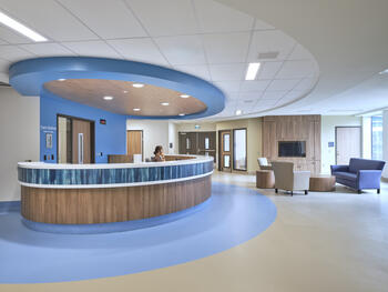 Image of a blue and wood rounded reception desk in the hospital. 