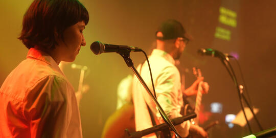 Guitar player and keyboard player look away from camera while performing.