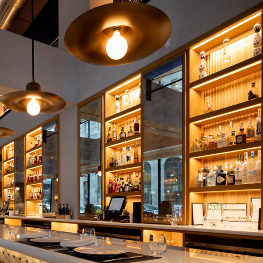 Photo of a bar with nicely organized bottles and mood lighting. 
