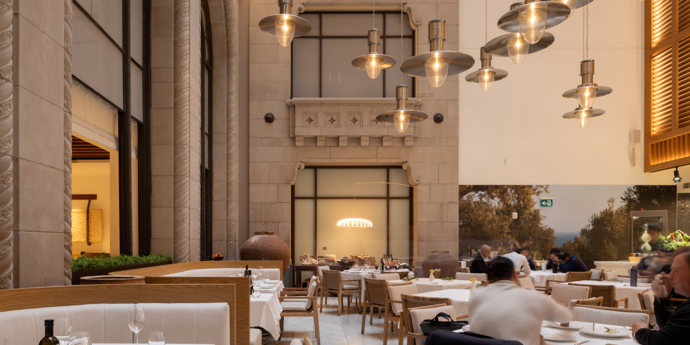 A restaurant interior featuring a heritage wall, eye-catching lighting features, and tables and chairs arranged for dining.