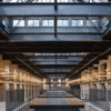 Artistic image of the Waterworks food hall from the upper level, with beams and glass ceiling visible.