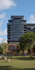 Vertical external shot of the residential portion of the building with the dog park next to the building in the foreground.